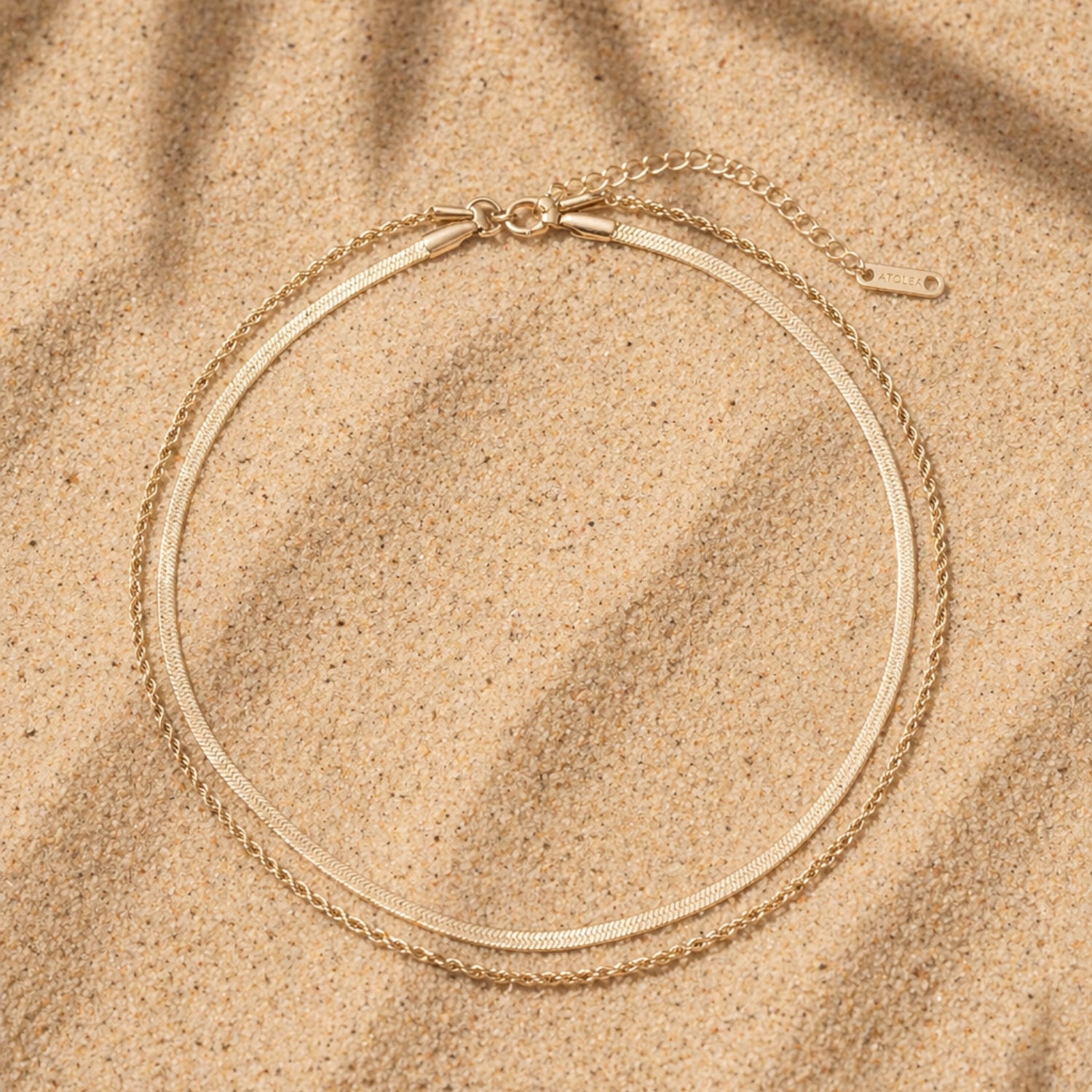 Ios Layered 14k Gold Bracelet Flat Lay On Sand, Double Chain Waterproof Jewelry