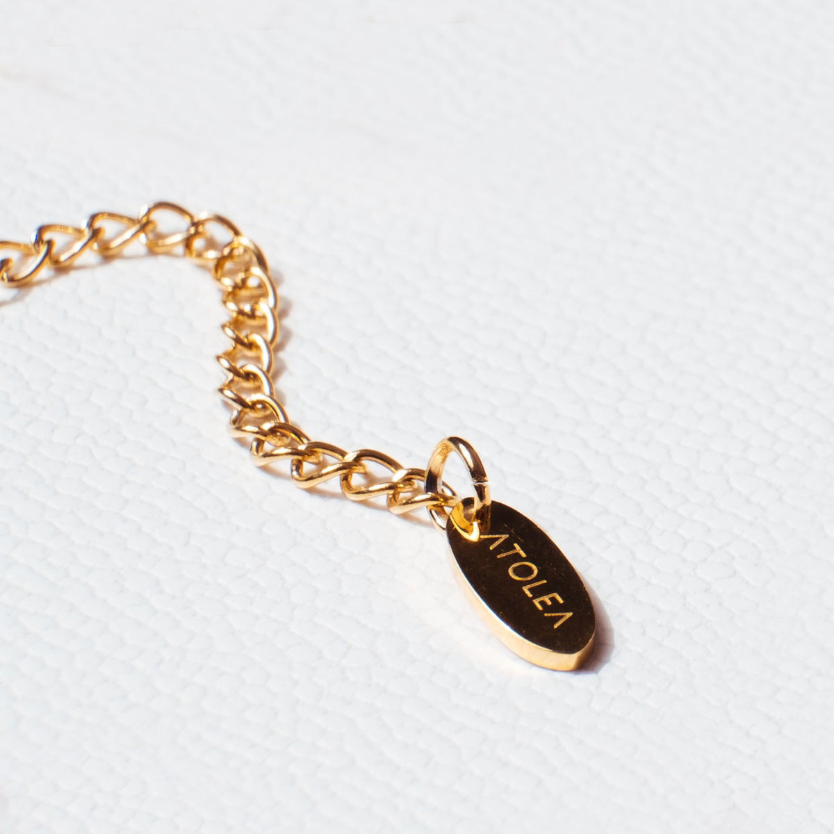 Gold chain extender with engraved Atolea logo tag